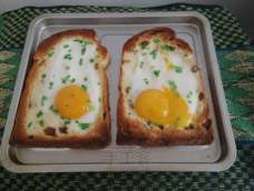 今天教大家做个简单的早餐，土司一片，用勺子把中间压扁，建议在烤盘上铺上烤纸压！然后把鸡蛋敲在上面，撒上葱！放入烤箱！5分钟！(ฅ>ω
