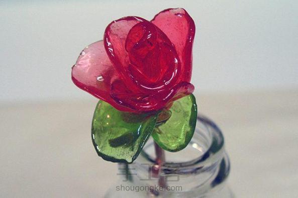 桌面上摆放着一朵玫瑰花，但是却看不出它是用硬糖做成的