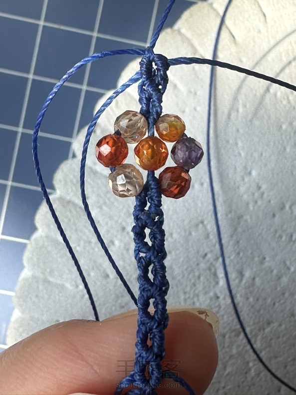 第一次编，珠子选大了，2根短线，一上一下夹在6个珠的小花旁边，编岀来很不平整。第二次编，2根短线先编了个反斜卷结，平整了但是小花整体有些变形。 第2张