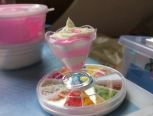 食玩杯中，粉、白色粘土叠放，用奶油土挤出图案放上水果切片