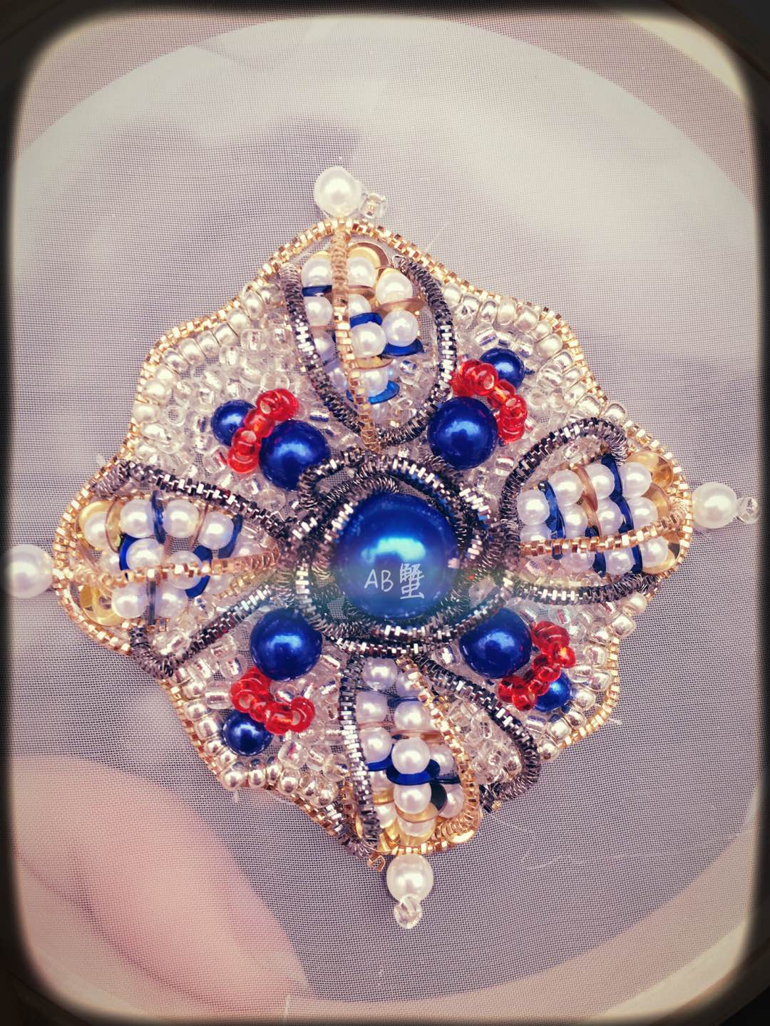 作品采用宝石蓝珠加正红珠再搭配金银边，形成复古而充满装饰感的效果。