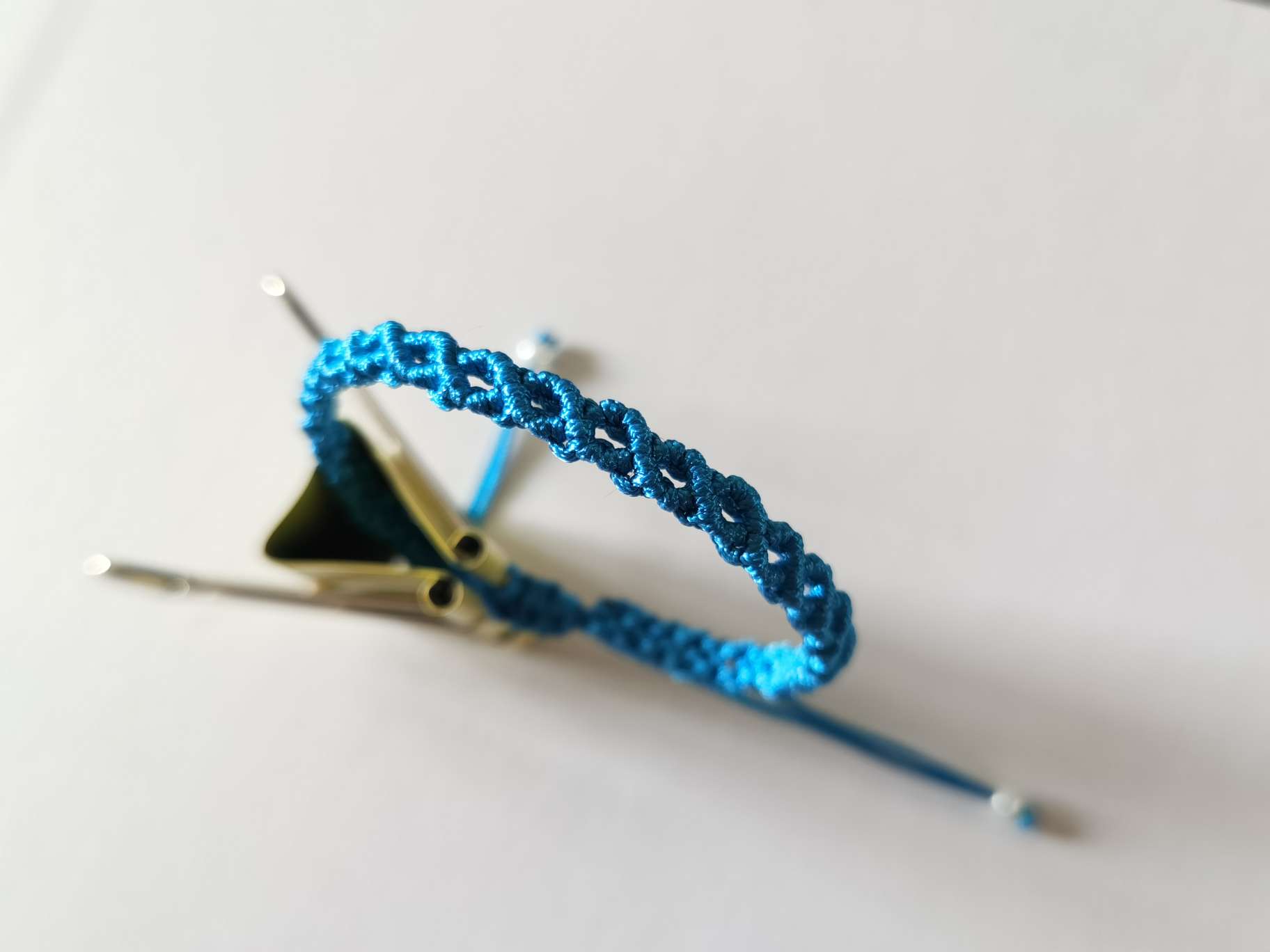 这个手链是由斜卷结编织出的镂空花纹组成，造型简单。