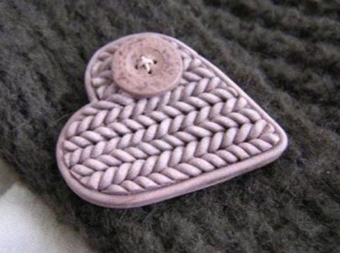 心形胸针，外形简朴，但独特的是将胸针的表面制作成针织的花纹，再配上一颗毛衣钮扣，毛衣的效果非常逼真，作为服饰、包装都是一款非常别致的饰品。
